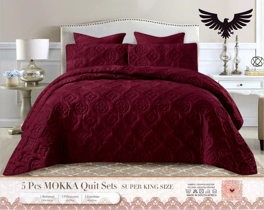 Burgundy quilt set on a bed with matching pillows.
